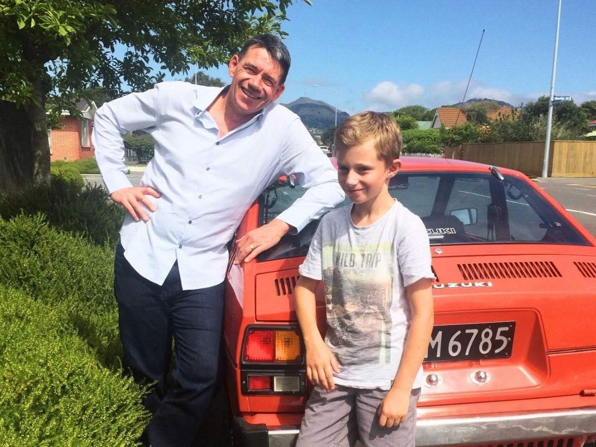 BBBS mentor Mac standing with 10-year-old Conn next to a red sports car