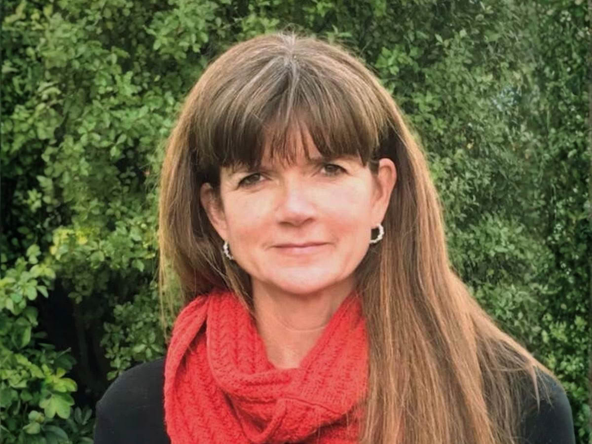 Volunteer Diane standing in front of some trees